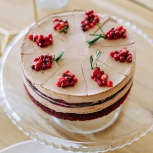 Chocolate dessert layered with cream, decorated with berries on a cake stand.