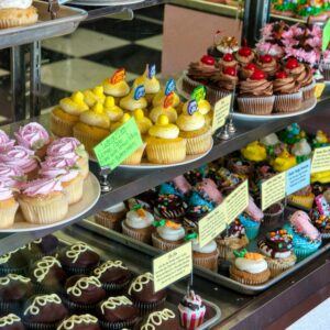 Showcase of colorful and decorative cupcakes in a bakery display.