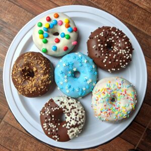 A vibrant assortment of decorated donuts placed on a white plate, perfect for any dessert lover.